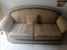 Vecchio divano in stoffa color verde con strisce gialle e rossastre