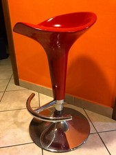 Sgabello con seduta rossa e supporto in acciaio.