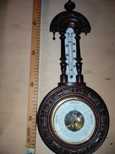 Barometro antico con cornice di legno intagliata.