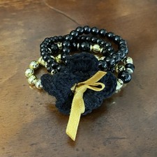 Bracciale da donna nero oro satinato bigiotteria perline dorate fiore uncinetto