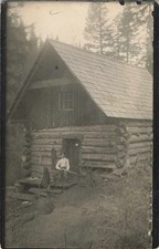 Antica capanna di tronchi RPPC anni '10 in legno con uomo e fucile vera foto cartolina Letol
