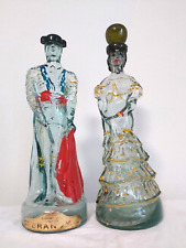 COPPIA VECCHIE BOTTIGLIE BRANDY VETRO STATUE NOGUERAS COMAS, MATADOR E SENORITA