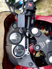 Moto Triumph 990 colore bordeaux con borse laterali e bauletto, copri serbatoio.