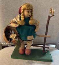 Bambola Lenci vintage su recinzione con cesto di attrezzi da giardino