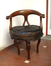Poltrona sedia in legno con seduta in pelle. I braccioli sono scolpiti.