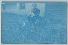 c1910's Little Boy seduto sulla falciatrice con cucciolo cane cianotipo RPPC foto cartolina