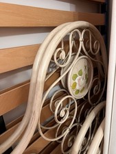 Lettino in ferro battuto con motivi decorati.