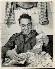 1953 Press Photo Robert Frigo opens a Red Cross gift box, NY port of embarkation