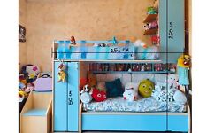 Cameretta bambini con scaletta contenitore, azzurra e beige. Letto e divano.