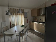 Cucina con elettrodomestici e living con divani e mobile porta tv