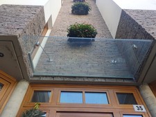 Tettoia o Pensilina sopra porta in cristallo e ancoraggio in acciaio