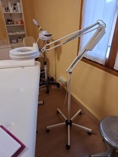 Lampada snodale estetista con lente integrata, su ruote. Colore bianco.