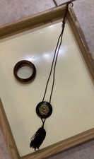 collana con pendente dorato e nappina e bracciale rigido nero e oro