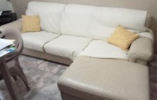 divano  penisola in pelle color panna con spalliera integra e seduta zigrinata