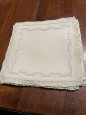 12 piccoli centrini in lino con ricamo intorno al bordo.