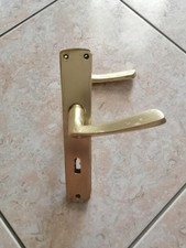 Maniglia dorata per porta con placca in alluminio.