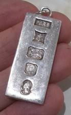 UN LINGOTTO / CIONDOLO IN ARGENTO STERLING (.925), 32,3 GRAMMI. MARCHIO DISTINTIVO BIRMINGHAM 1977.