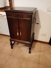grammofono vintage a manovella su mobiletto in legno, con dischi e puntine 