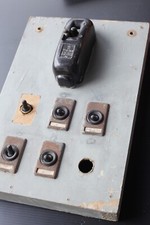 B) vecchio quadro elettrico in legno Bticino con vari interruttori.