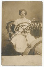 Antica donna afroamericana RPPC al volante di un'auto. Cartolina Automobile